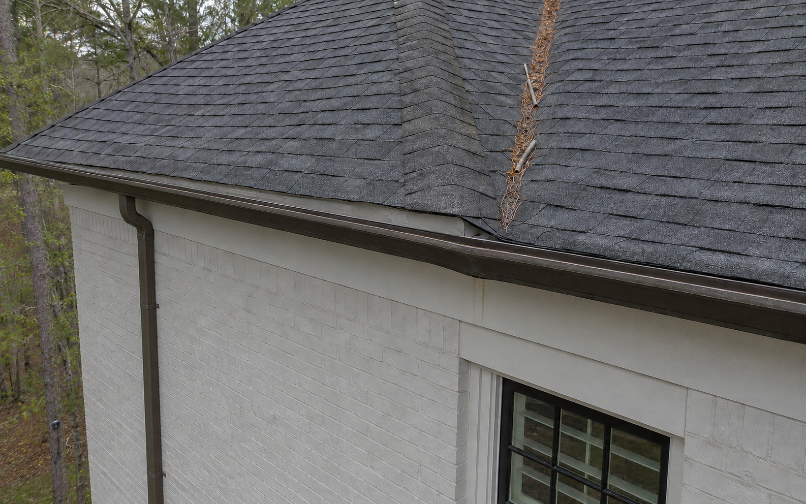 Aerial inspection view showing a small gutter separation and water staining at an upper-story roof edge