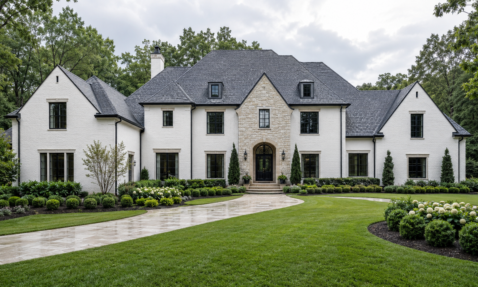 Custom white brick English manor with limestone entry, natural slate roof, black gutters and coordinated black steel windows